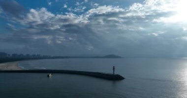 Deniz kenarındaki uzun kırmızı ve beyaz çizgili deniz feneri. Yaz tatili, deniz konseptinde tatil