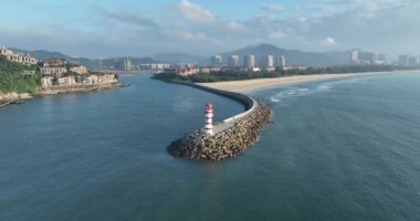 Deniz kenarındaki uzun kırmızı ve beyaz çizgili deniz feneri. Yaz tatili, deniz konseptinde tatil