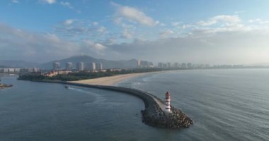 Deniz kenarındaki uzun kırmızı ve beyaz çizgili deniz feneri. Yaz tatili, deniz konseptinde tatil