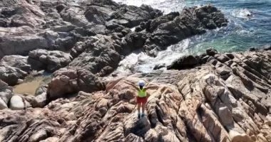 Denizde kayalıklarda sportif bir kadın.