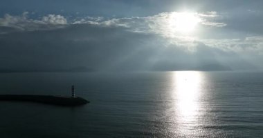 Deniz kenarındaki uzun kırmızı ve beyaz çizgili deniz feneri. Yaz tatili, deniz konseptinde tatil