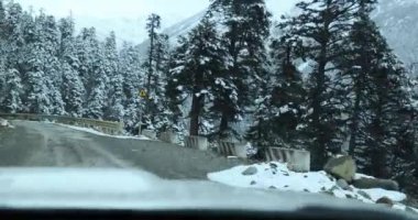 Karla kaplı yolda ve dağlarda giden araba.