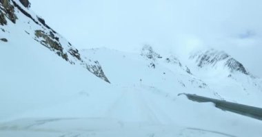 Karla kaplı yolda ve dağlarda giden araba.