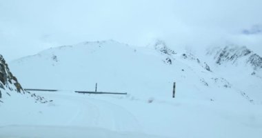 Karla kaplı yolda ve dağlarda giden araba.