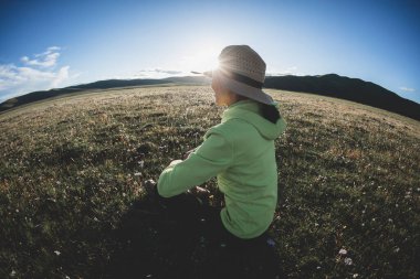 Kadın yüksek rakımlı dağlarda çiçeklere ve çimenlere oturur.