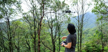 People remote control a flying drone in summer forest