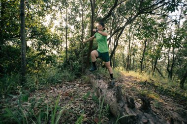 Woman trail runner running at tropical forest mountain peak