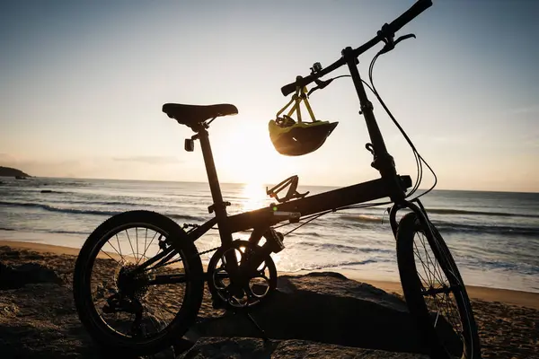 日出海滨岩石上的可折叠自行车 — 图库照片