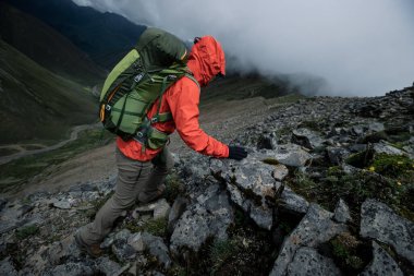 Tibet 'te dağın tepesine tırmanan bir kadın yürüyüşçü
