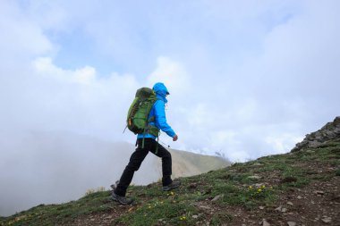 Tibet 'te dağın tepesine tırmanan bir kadın yürüyüşçü