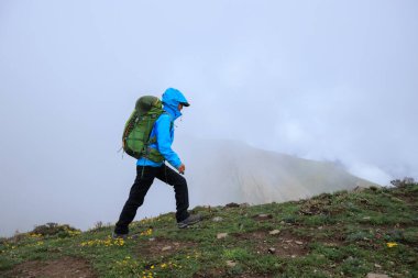 Tibet 'te dağın tepesine tırmanan bir kadın yürüyüşçü