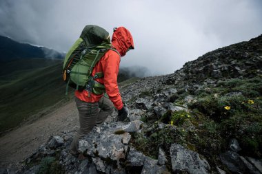Tibet 'te dağın tepesine tırmanan bir kadın yürüyüşçü
