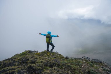 Dağın tepesinde yürüyüş yapan bir kadın.