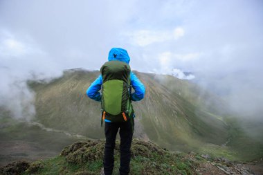 Dağın tepesinde yürüyüş yapan bir kadın. 