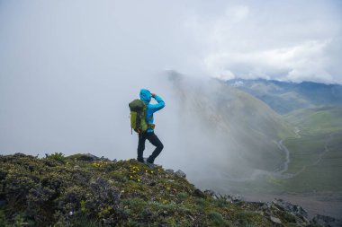 Dağın tepesinde yürüyüş yapan bir kadın.