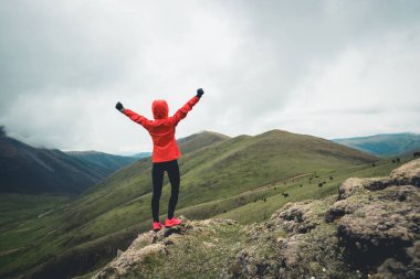 Yükseklik dağ zirvesinde kollarını açan kadın koşucu.