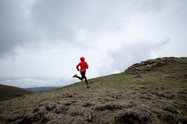 Yüksek irtifa dağ zirvesine koşan kadın koşucu.