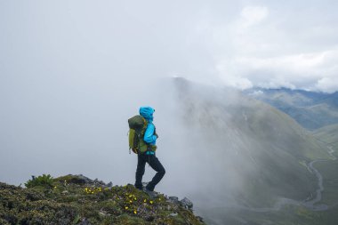 Dağın tepesinde yürüyüş yapan bir kadın.