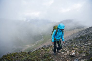 Tibet 'te dağın tepesine tırmanan bir kadın yürüyüşçü