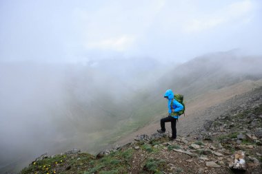 Dağın tepesinde yürüyüş yapan bir kadın.