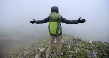 Kadın yürüyüşçü, dağın tepesindeki uçurumun keyfini çıkar. Tibet 'teki kar kaplı dağlara bak.