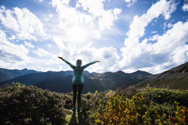 Başarılı bir kadın yüksek rakımlı dağ zirvesinde uzuvlarını uzattı.