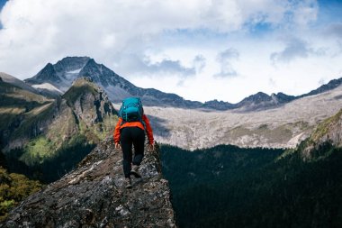 Tibet 'te dağın tepesine tırmanan bir kadın yürüyüşçü