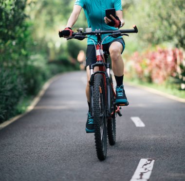 Yazın tropikal park yolunda akıllı telefon kullanan bir kadın.