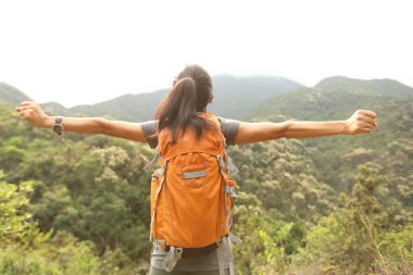 Neşeli mutlu kadın, sabah dağının tepesinde manzaranın tadını çıkarıyor.