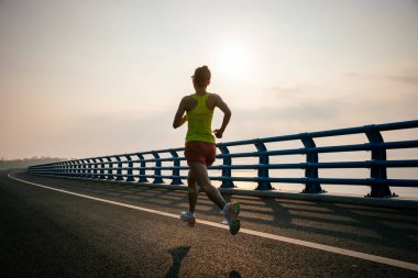 Fitness kadın koşucusu deniz kenarındaki köprüde koşuyor.