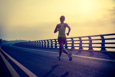 Fitness kadın koşucusu deniz kenarındaki köprüde koşuyor.