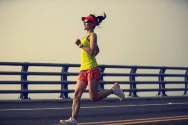  Fitness kadın koşucusu deniz kenarındaki köprüde koşuyor.