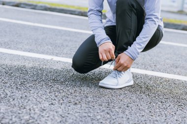 Tropikal parkta koşan sağlıklı yaşam tarzı sporcu Asyalı kadın ayakkabı bağı bağlıyor