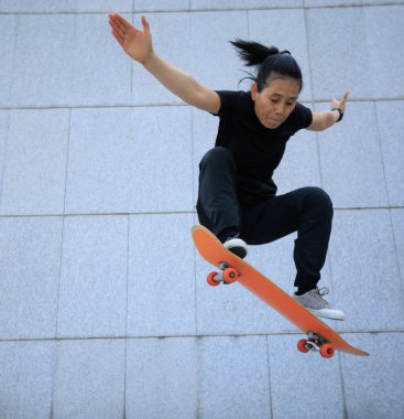 Modern şehirde Asyalı kaykaycı kadın.