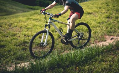 Gündüz vakti dağ yolunda bisiklet süren bir kadın 