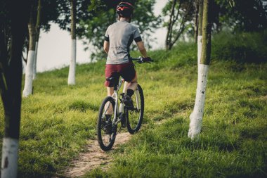 Dağ yolunda bisiklet süren genç bir kadın. 