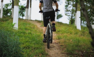 Dağ yolunda bisiklet süren bir kadının gündüz görüntüsü