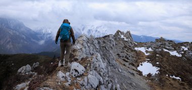 Tibet 'te dağın tepesinde yürüyüş yapan bir kadın.