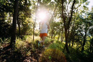 Kadın koşucu orman yolunda koşuyor.