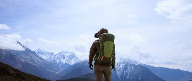 Tibet 'te dağın tepesinde yürüyüş yapan bir kadın.