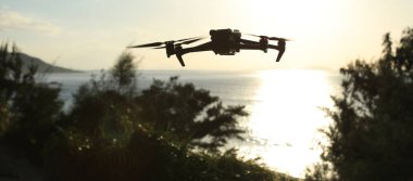 Gün doğumunda fotoğraf çeken uçan dron silueti.