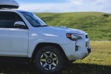 Mavi gökyüzünün altındaki çayır dağında off-road arabası.