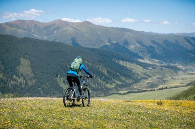 Ormanın tepesinde dağ bisikleti süren bir kadın.