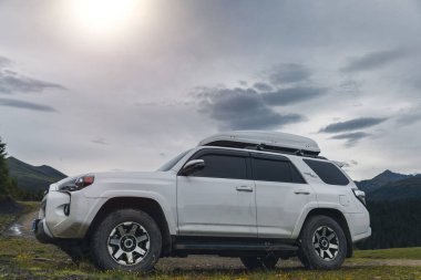 Gökyüzünün altındaki çayırlık bir dağın üzerinde off-road arabası.