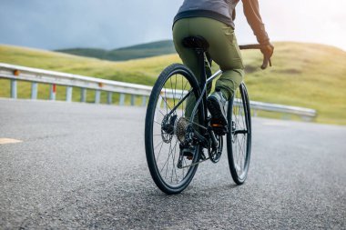 Riding bike on grassland mountain top trail clipart