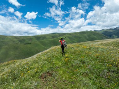 Dağ bisikleti süren bir kadın Çiçekli çayırların tepesinde