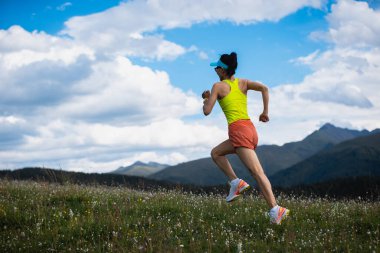 Fitness kadın koşucusu çiçek açan çayırların tepesinde koşuyor.