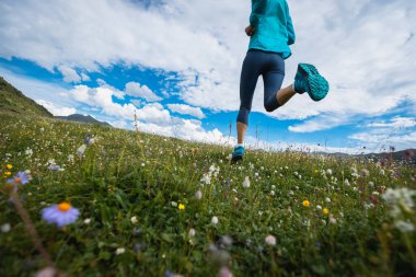 Fitness kadın koşucusu çiçek açan çayırların tepesinde koşuyor.