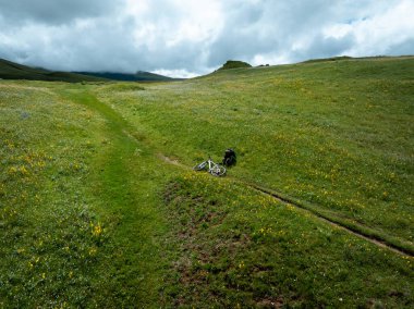 Çiçekli çayır dağlarında bisiklet sürmenin havadan görünüşü