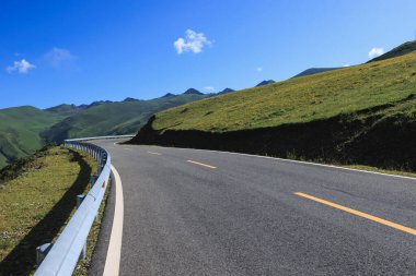 Çiçekli çayırların tepesindeki asfalt yolda.